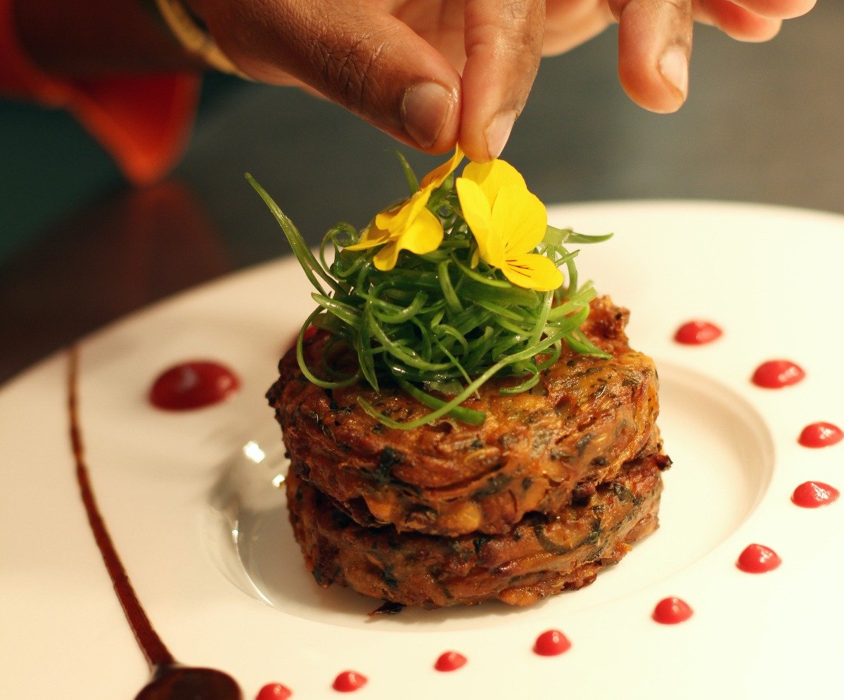 Best Indian Takeaway from Amesbury Tandoori Two pakoras piled on a plate with shredded spring onion and topped with yellow flowers